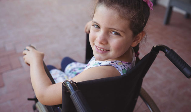 High angle portrait of schoolgirl sitting on wheelchair